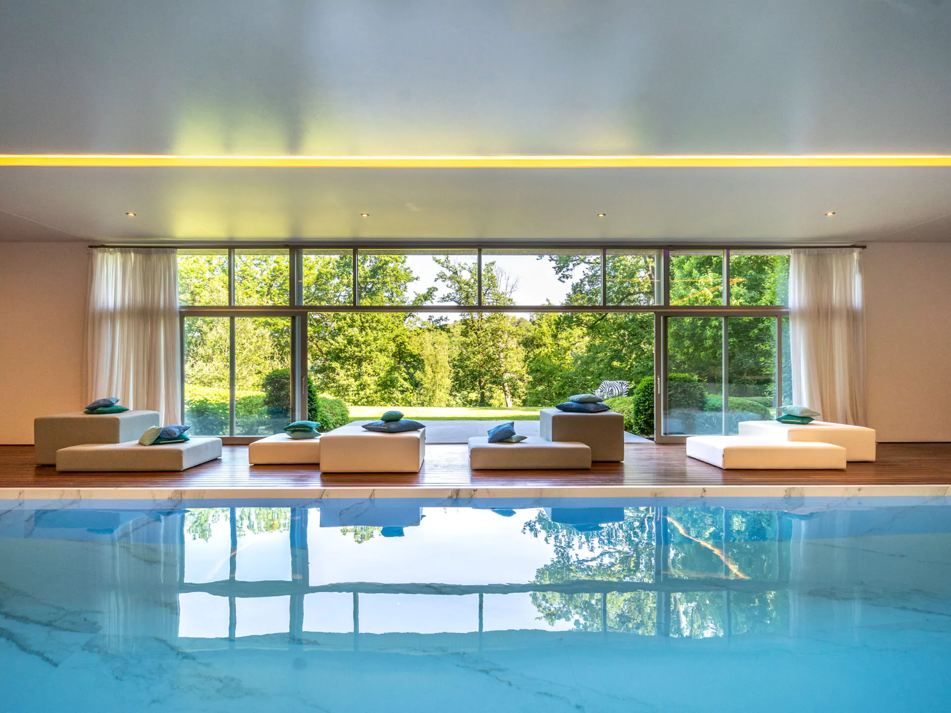 Lichte wellnessruimte met luxe binnenzwembad en uitzicht op een aangelegde tuin in Grez-Doiceau, vlak bij een prestigieuze golfbaan in Waals-Brabant.