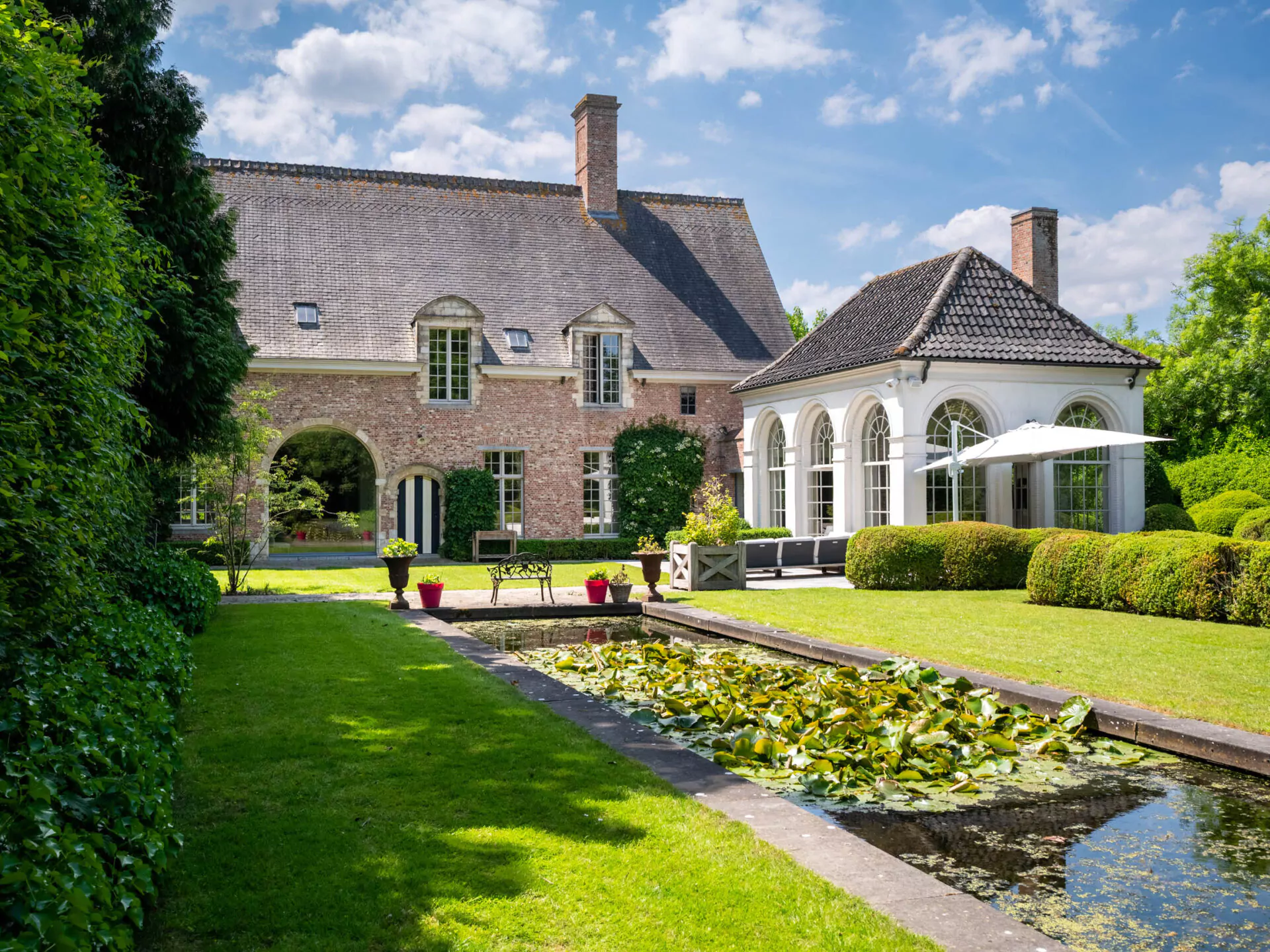 Klassiek bakstenen huis met aangelegde tuin, vijver en glazen uitbouw in Sint-Martens-Latem